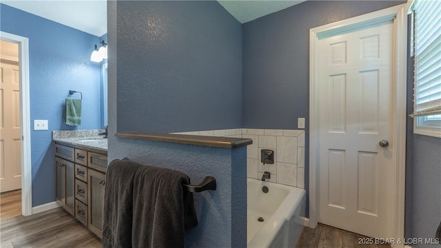 907 Sunnyview Cir, Eldon, MO 65026 - full bath with wood finished floors, a garden tub, vanity, baseboards, and a textured wall