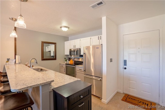 kitchen with stainless steel appliances, a sink, a kitchen breakfast bar, a peninsula, and light tile patterned flooring