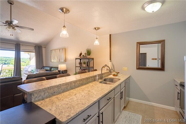 kitchen featuring a sink, a peninsula, baseboards, lofted ceiling, and light tile patterned floors