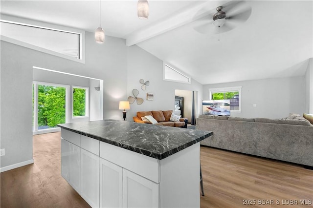 kitchen with white cabinets, beam ceiling, light wood-style flooring, open floor plan, and a kitchen island
