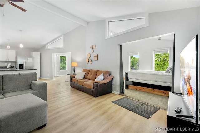 living room featuring beam ceiling, high vaulted ceiling, healthy amount of natural light, ceiling fan, and light wood-type flooring