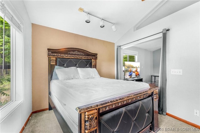 bedroom featuring lofted ceiling, track lighting, and baseboards