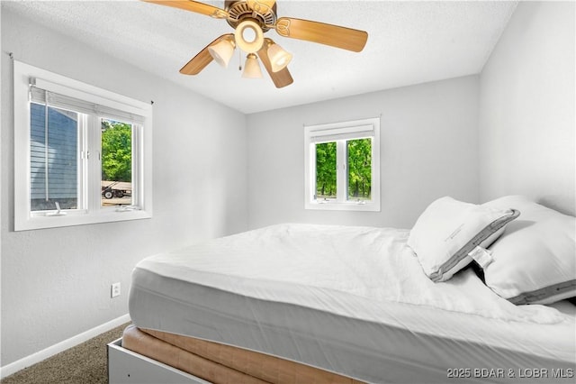 bedroom featuring baseboards, multiple windows, carpet, and a ceiling fan