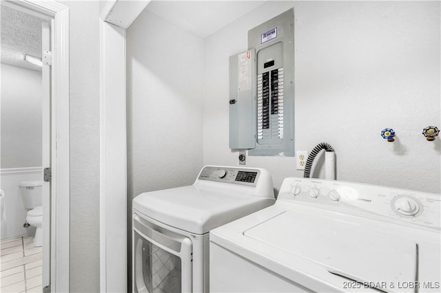 laundry room with electric panel, washer and clothes dryer, and light tile patterned floors