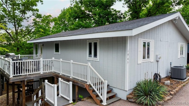 rear view of house with a wooden deck, central AC, stairs, and roof with shingles