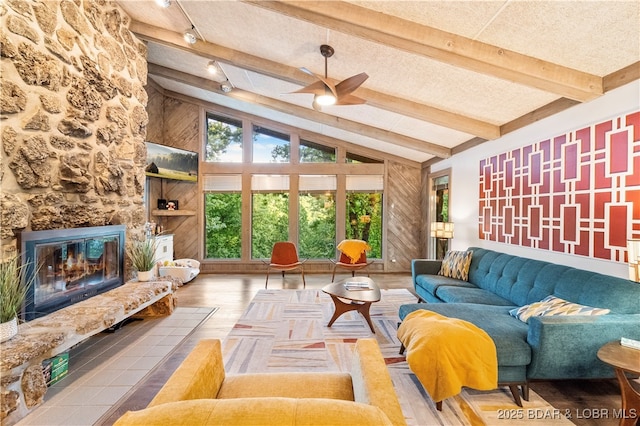 living room featuring a ceiling fan, wood finished floors, and a stone fireplace