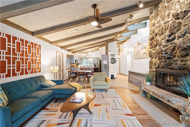 living area featuring a chandelier, a ceiling fan, wood finished floors, a fireplace, and a textured ceiling