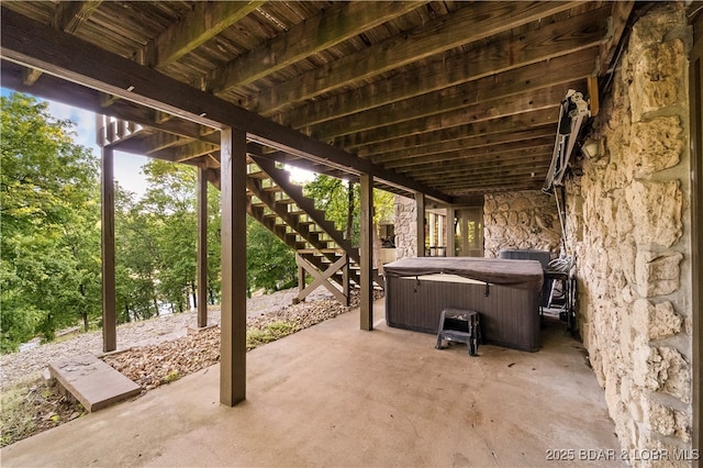 view of patio / terrace with a hot tub and stairs