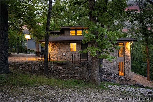 back of property at dusk with stone siding