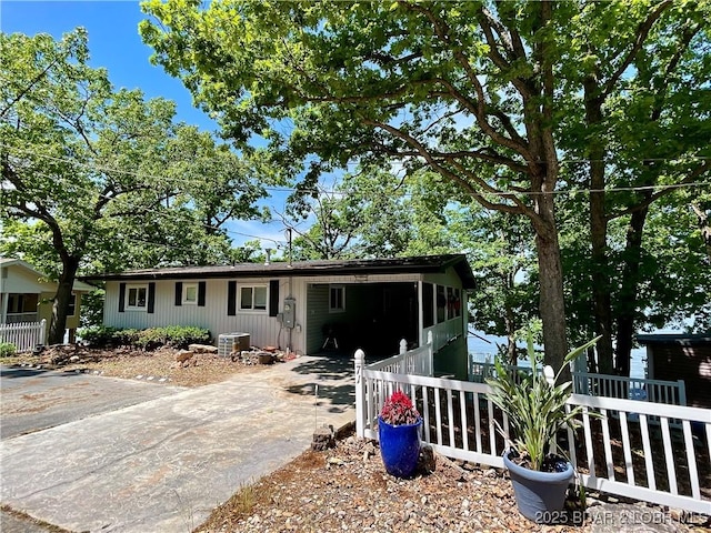 view of front of house featuring central AC unit, driveway, fence, and an attached carport