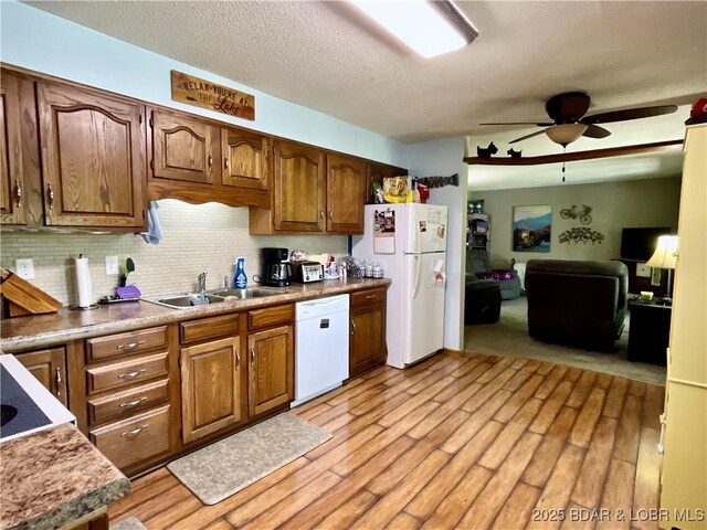 kitchen featuring white appliances, a sink, ceiling fan, light wood-style floors, and decorative backsplash