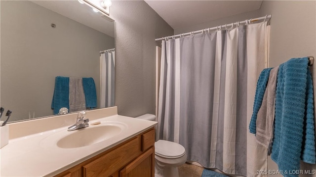 bathroom featuring toilet, vanity, a textured wall, and a shower with curtain