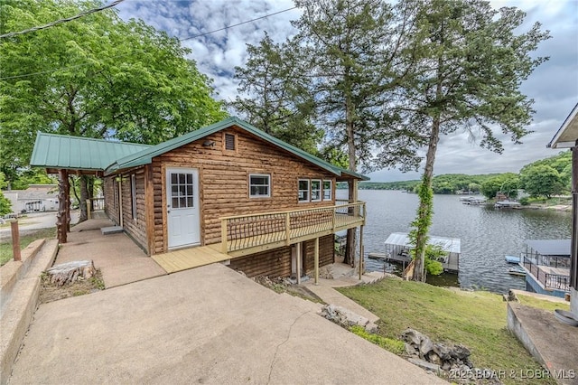 view of front facade with a water view, metal roof, a boat dock, and a standing seam roof