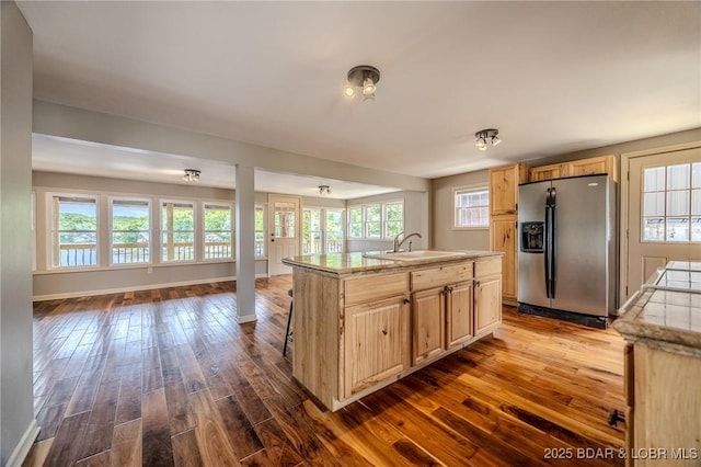 kitchen with stainless steel fridge with ice dispenser, open floor plan, light brown cabinets, dark wood-style flooring, and a sink