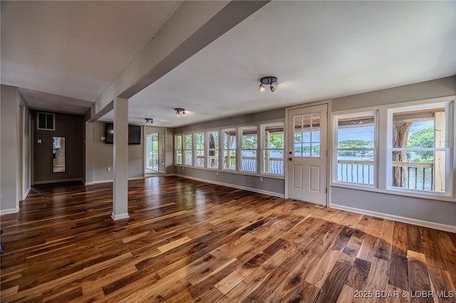 unfurnished living room featuring wood finished floors and baseboards