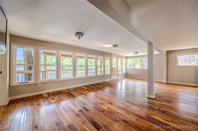 unfurnished living room featuring wood finished floors, baseboards, and plenty of natural light