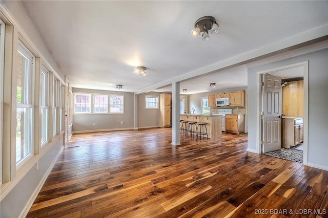 unfurnished living room featuring dark wood finished floors and baseboards