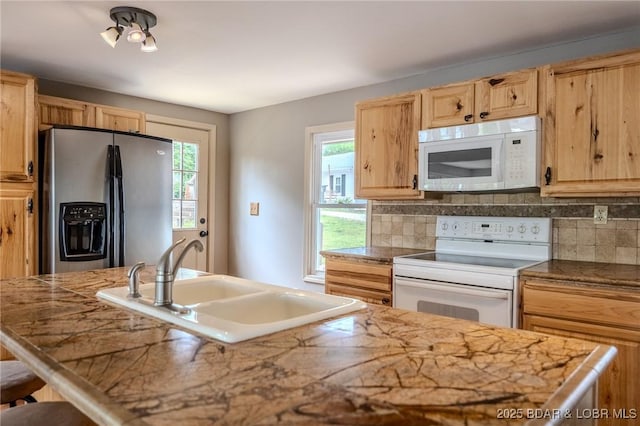 kitchen with white appliances, a sink, tasteful backsplash, and plenty of natural light