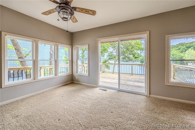 carpeted spare room featuring baseboards and a ceiling fan