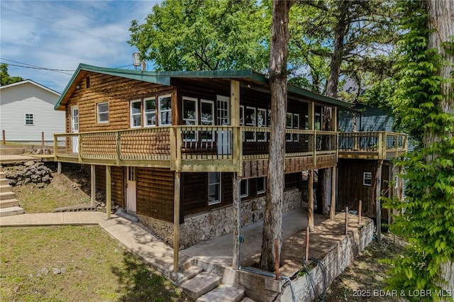 back of house with a patio area, a wooden deck, and stone siding