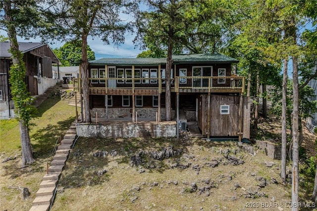 rear view of house with a wooden deck, a patio, and stone siding