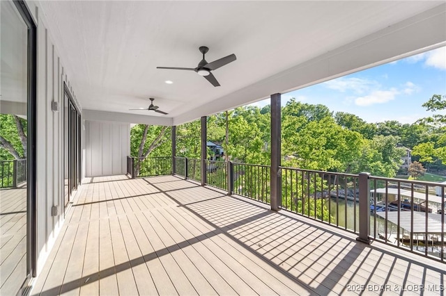 wooden terrace featuring ceiling fan, view of wooded area, and a water view