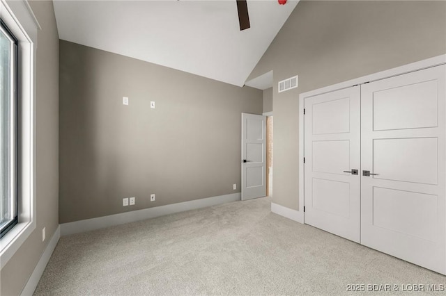 unfurnished bedroom with carpet, baseboards, a closet, high vaulted ceiling, and ceiling fan