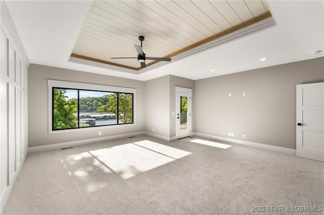 unfurnished room featuring a raised ceiling, wood ceiling, baseboards, light carpet, and ceiling fan