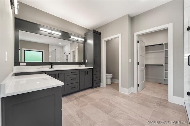 full bath with a stall shower, toilet, vanity, a walk in closet, and baseboards