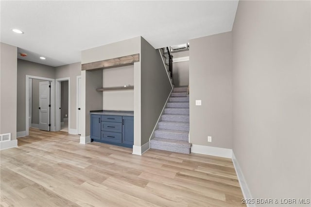 stairway featuring wood finished floors, baseboards, recessed lighting, and bar area