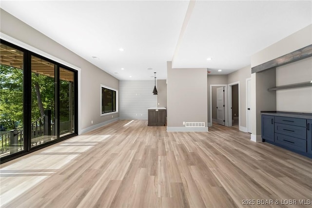 unfurnished living room featuring baseboards, light wood-type flooring, and recessed lighting