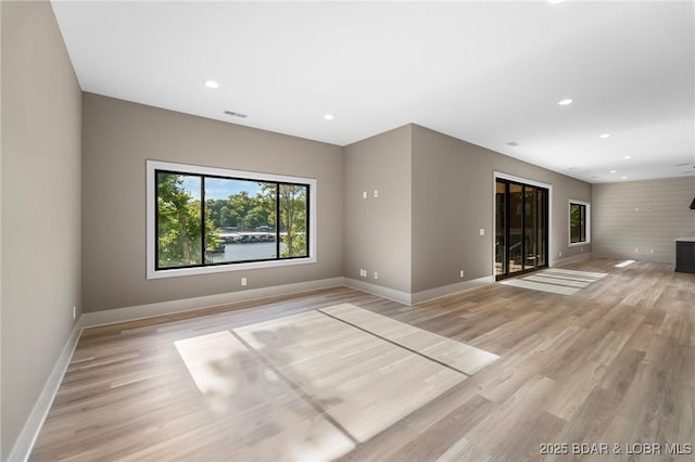 unfurnished living room with baseboards, recessed lighting, and light wood-style floors