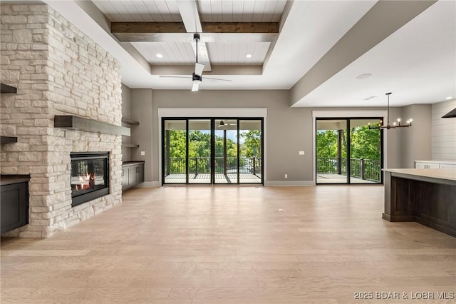unfurnished living room featuring light wood-style flooring, a stone fireplace, beam ceiling, ceiling fan, and baseboards