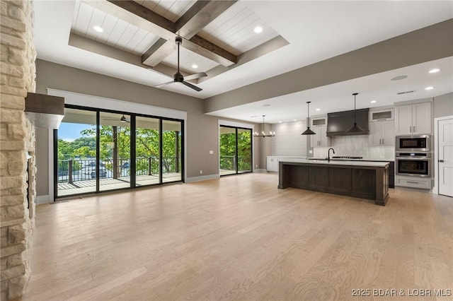 kitchen with oven, open floor plan, light countertops, beam ceiling, and built in microwave
