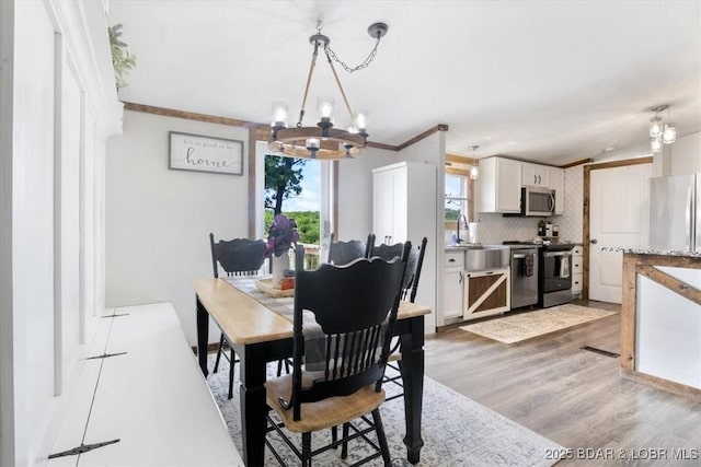 dining room with a chandelier, light wood-style flooring, and ornamental molding