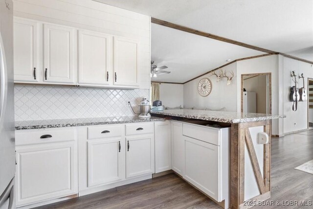 kitchen with a peninsula, white cabinets, dark wood finished floors, and lofted ceiling