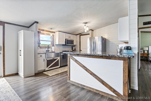 kitchen featuring stainless steel appliances, dark wood finished floors, a sink, tasteful backsplash, and white cabinetry