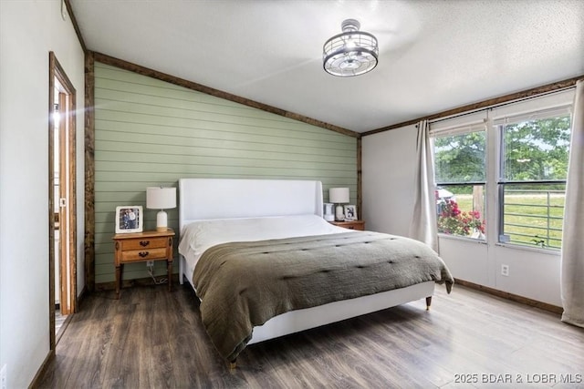 bedroom featuring lofted ceiling, wood finished floors, baseboards, wood walls, and a chandelier