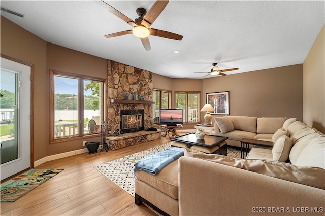 living area featuring baseboards, healthy amount of natural light, ceiling fan, and light wood-style floors