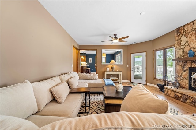 living room featuring wood finished floors, a ceiling fan, baseboards, and a fireplace