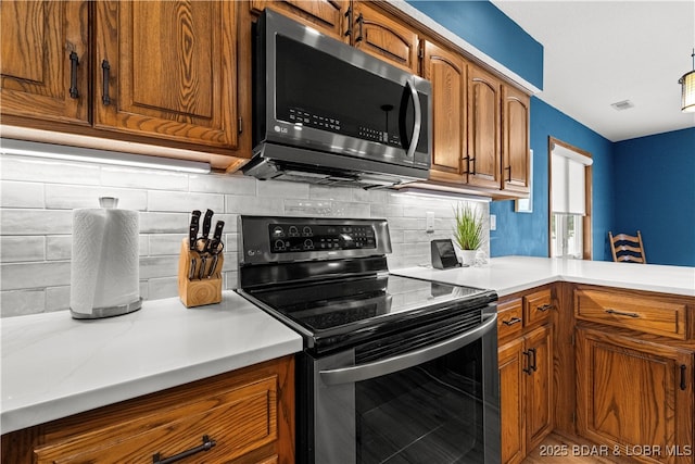 kitchen featuring appliances with stainless steel finishes, brown cabinetry, and light countertops
