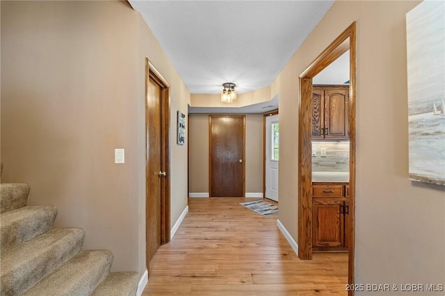 foyer with light wood-type flooring, stairway, and baseboards