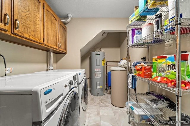 clothes washing area featuring washer and dryer, electric water heater, cabinet space, and light marble finish flooring