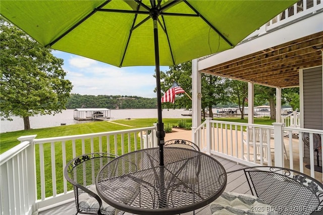wooden terrace with outdoor dining area, a lawn, and a water view