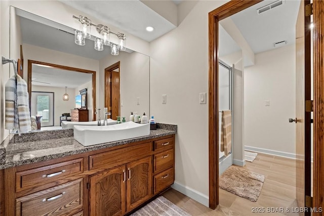 bathroom with a stall shower, vanity, baseboards, and wood finished floors