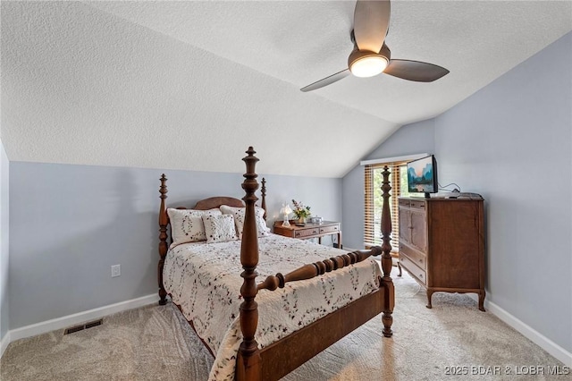 bedroom with a textured ceiling, vaulted ceiling, carpet flooring, baseboards, and a ceiling fan