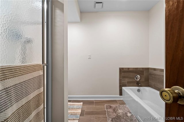 bathroom featuring baseboards and a bath