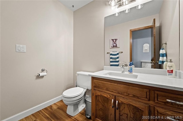bathroom featuring wood finished floors, toilet, baseboards, and vanity