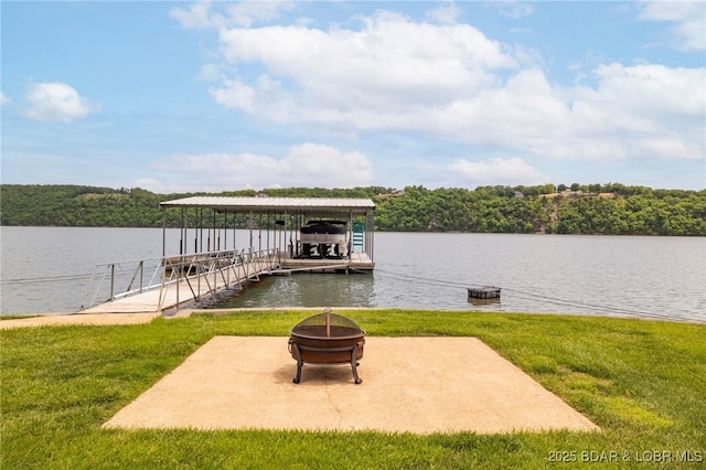 dock area featuring an outdoor fire pit, boat lift, a water view, and a lawn