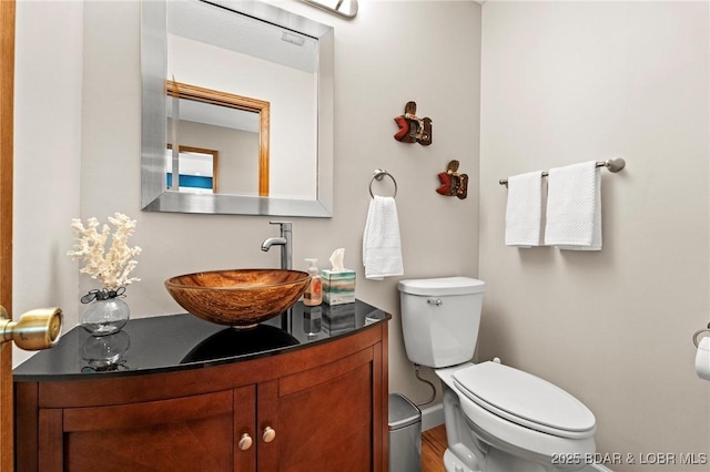 half bathroom with vanity, toilet, and wood finished floors